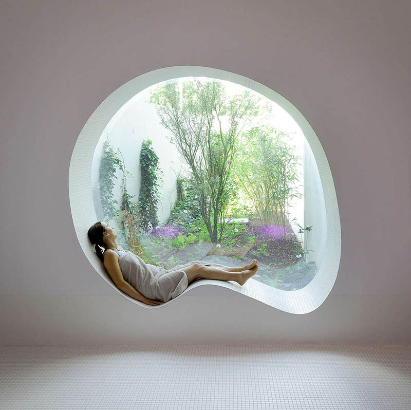 Perfect for daydreaming, this modern white curved window seat looks out over a tranquil garden. 