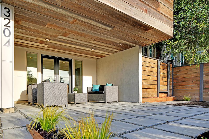 Beside the front door, this modern house cantilevers out creating a perfect covered patio spot. Smooth cement pavers ensure it's easy enough to walk around without shoes. 