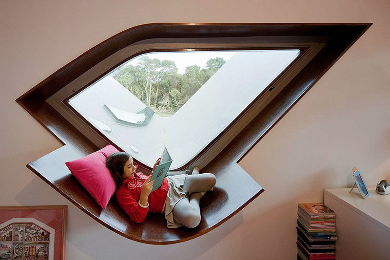 This geometrically shaped window has a built-in wood frame with an additional support that acts as a curved window seat.