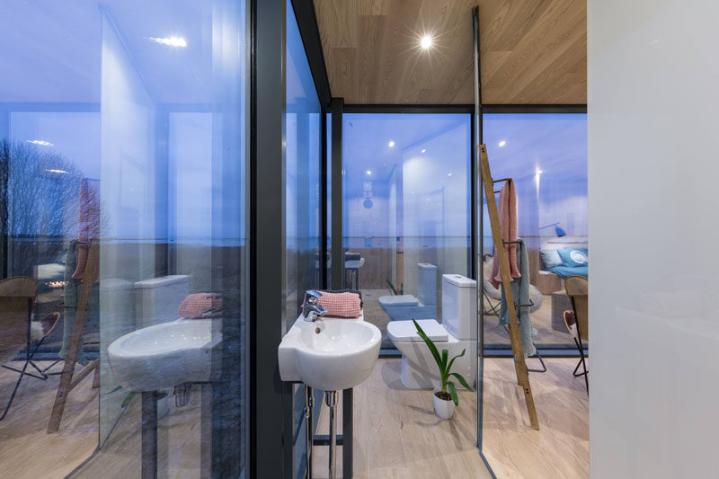 In front of the shower, a small freestanding sink just before the toilet faces outside in this modern bathroom. 