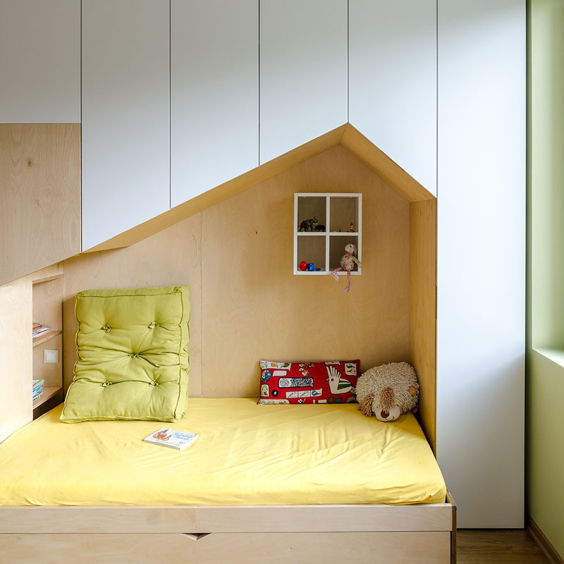 This fun and modern kid's bedroom has a custom wall unit that features plenty of storage and two beds in mini houses.