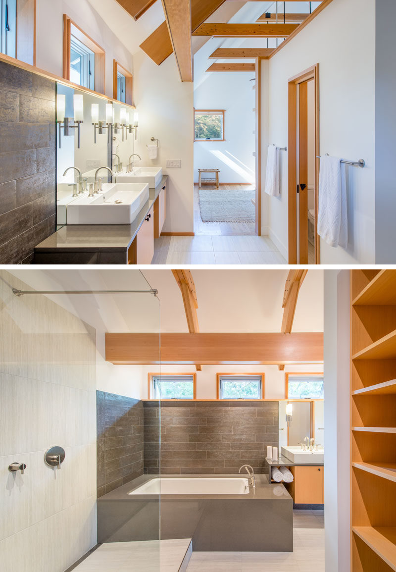 In this mostly white and wood modern master bathroom, the bath sits at the end of the vanity and is surrounded by grey tile.