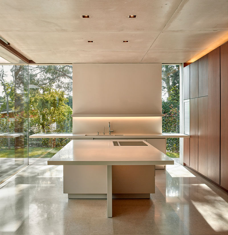 In this minimalist kitchen, floor-to-ceiling windows provide ample natural light, while a square kitchen island creates plenty of space for food preparation.