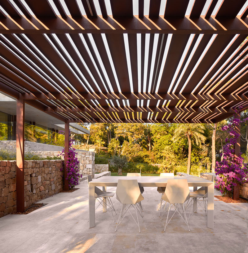 This modern house in Spain has an alfresco dining area that sits beneath a pergola.