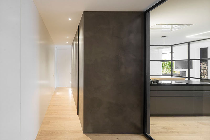 A powder room is hidden within a dark box in the hallway of this modern penthouse.