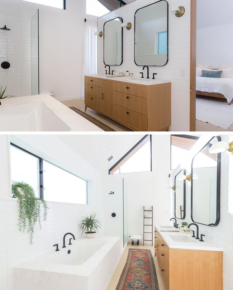 This modern master bathroom features a dual sink wood vanity, a bathtub and a walk-in shower.