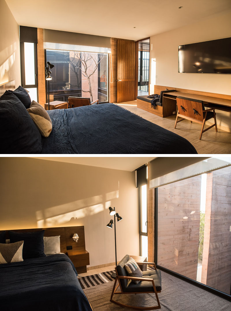 This modern bedroom has a built-in wood bench and desk, and large windows provide views of the courtyard below.