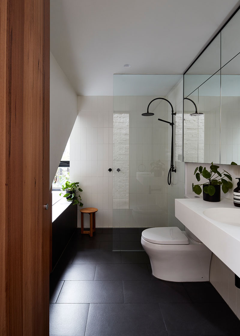 In this modern bathroom, simple white walls and tiles are paired with black floor tiles and a floating vanity.