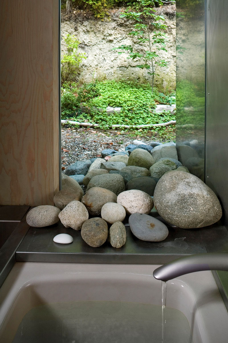 In this modern cabin bathroom, a window allows the stones appear to flow from the forest straight into the bathroom.