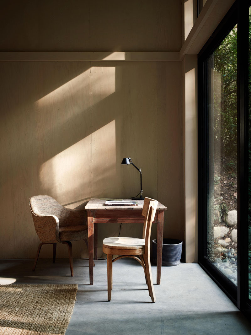 Large windows throughout this modern cabin provide natural light filtered by the trees.