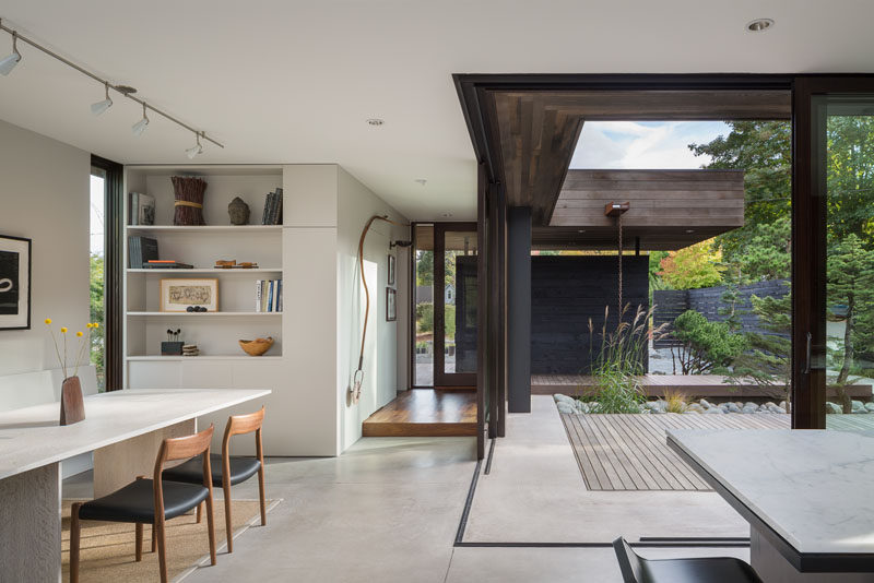 The dining room in this modern house opens up to a small courtyard surrounded by landscaping.