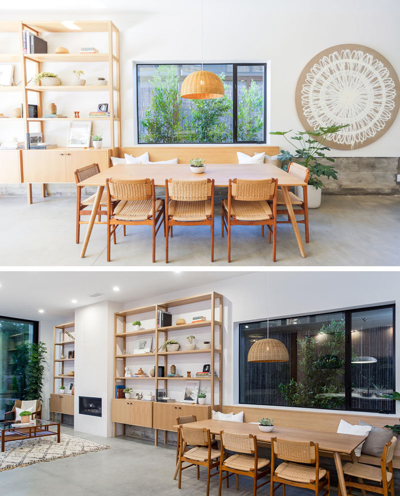 This custom wood shelving unit continues to become a bench that provides seating for the dining table. The floor throughout the main level of this modern house is concrete.