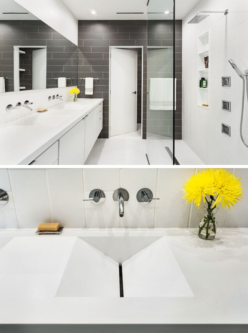 In this modern master bathroom, grey tiles have been used to create an accent wall, while a long vanity has dual sinks with an interesting design.