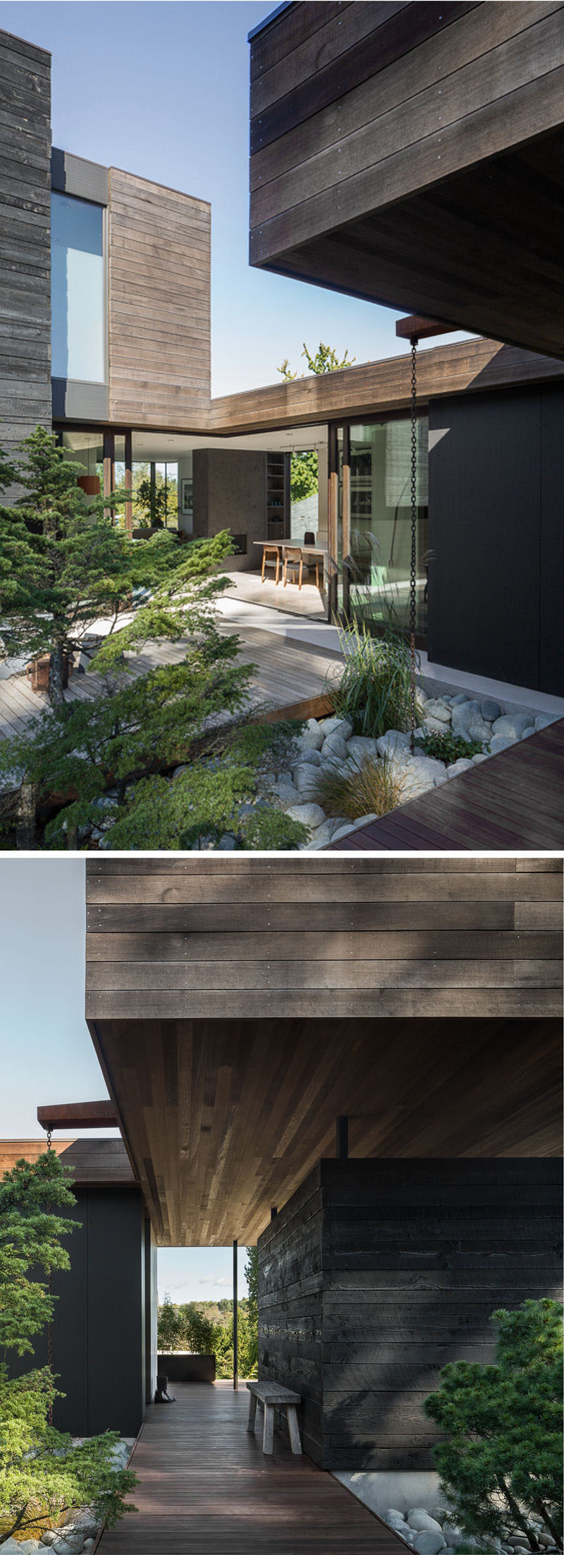 This modern house has a wooden path that leads from the sidewalk to the front door and a courtyard that's surrounded by plants.