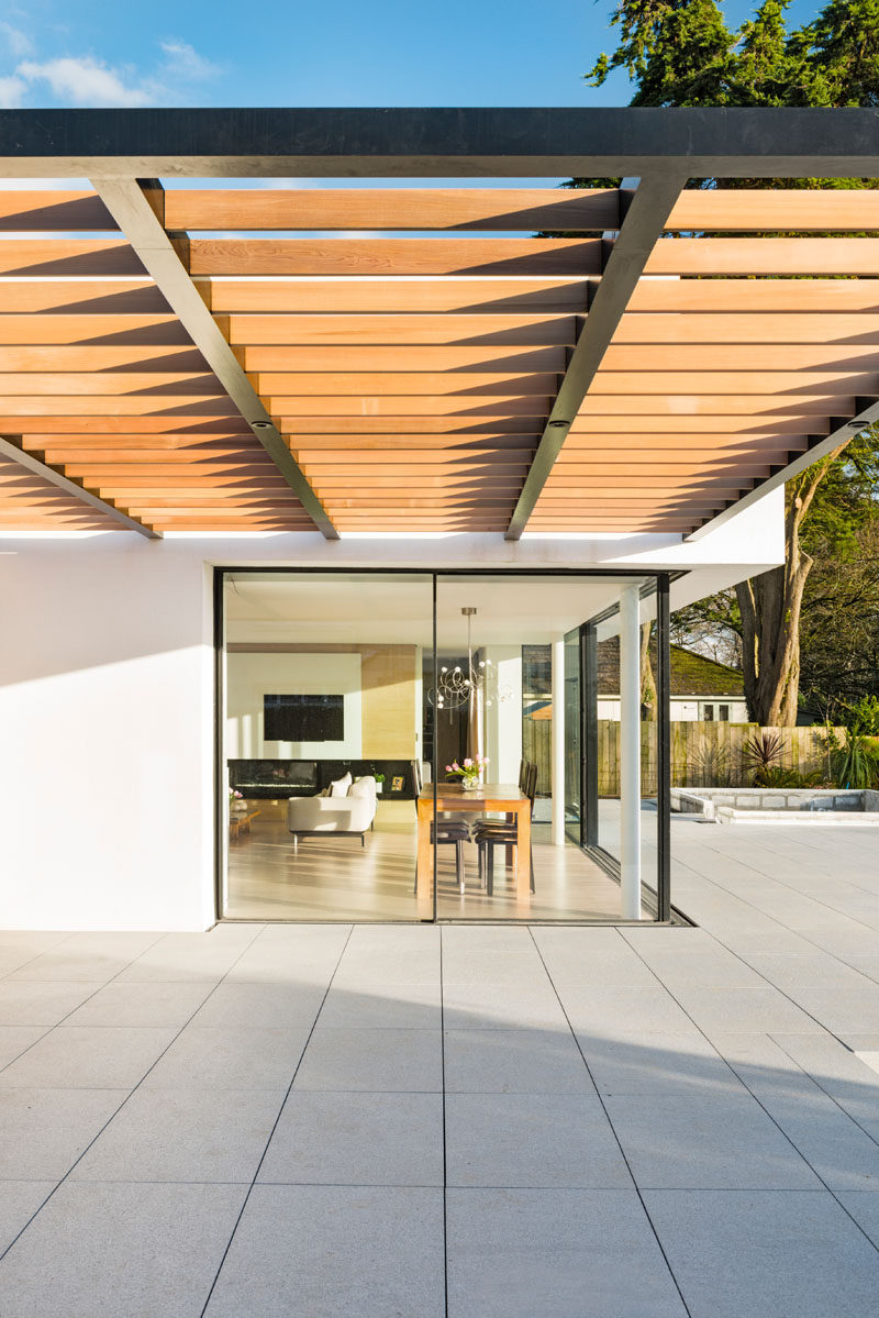 This modern house has a wood pergola that provides shade on a sunny day.