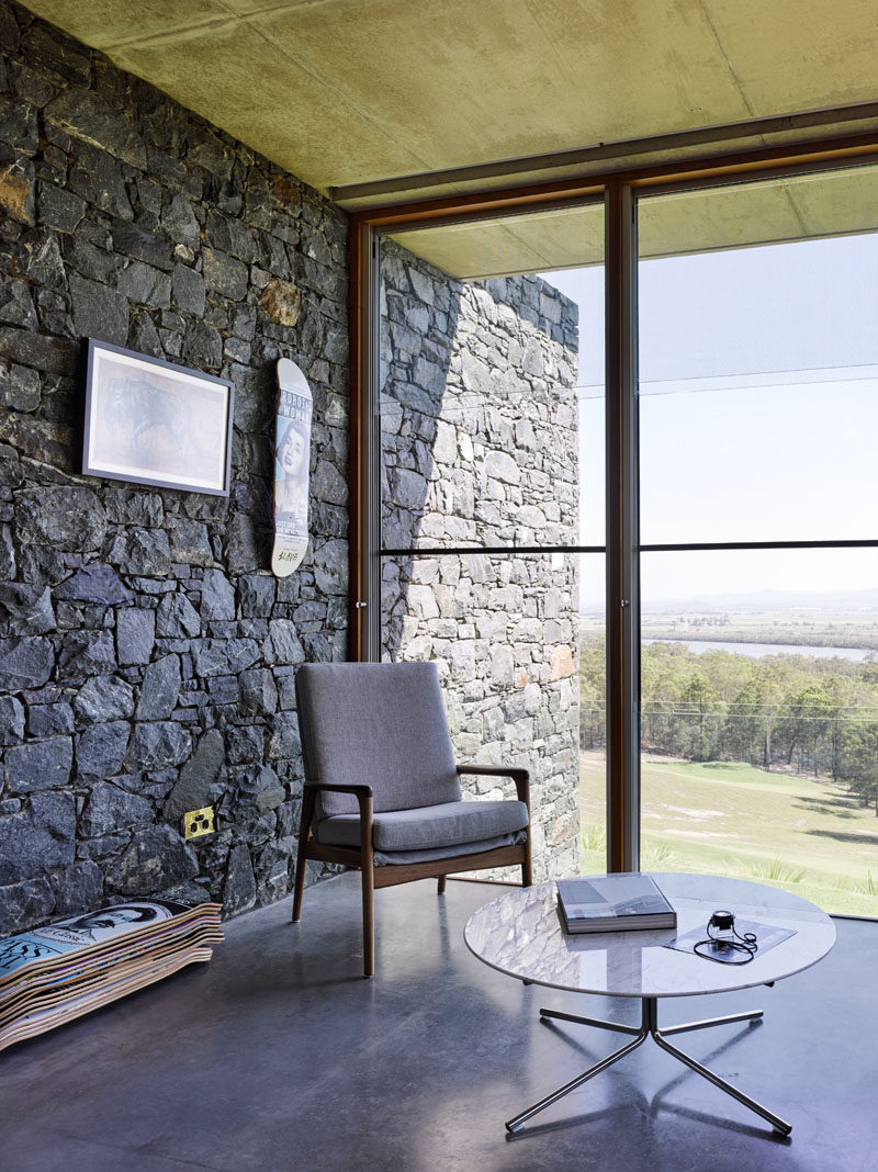 Large windows frame the picturesque views of the landscape from this modern house, while the bluestone walls travel from the exterior of the house, through to the interior.