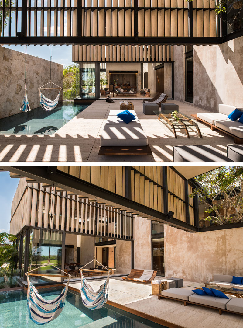 Two hammocks hang above this modern swimming pool, while a stone wall creates privacy for those swimming. 