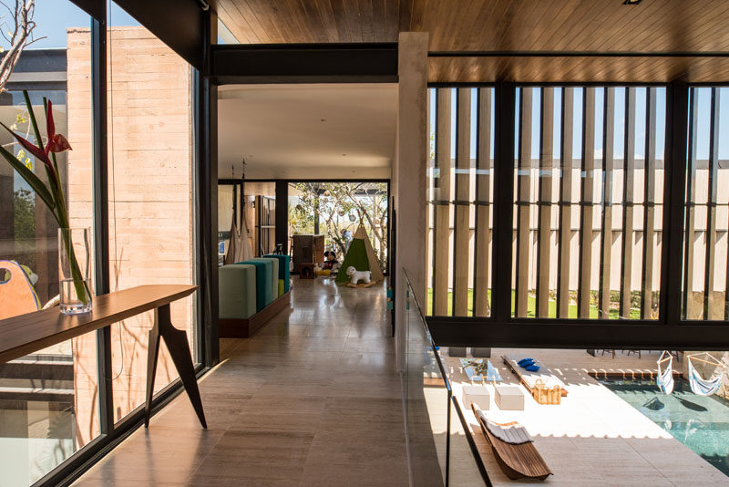 This modern house has a small bridge that looks down to the courtyard on the left, and on the right, it looks down to the outdoor entertaining area and pool.