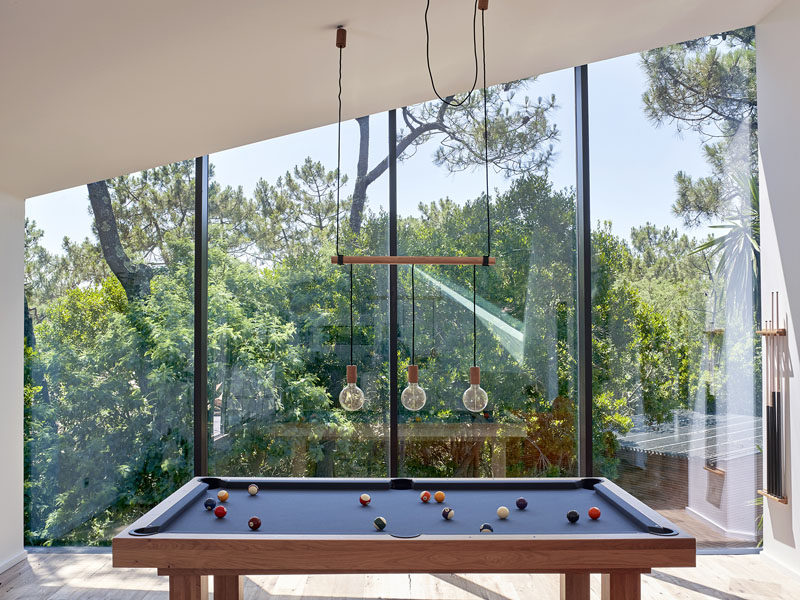 Large floor-to-ceiling windows follow the line of the roof in the games room of this modern holiday house.