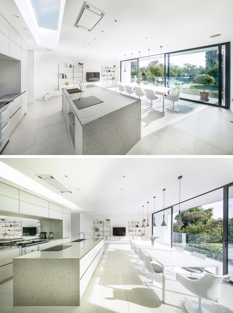 This kitchen and dining area, which are located in a cantilevered portion of this modern house, are filled with natural light from the large sliding glass doors and a skylight above the kitchen.