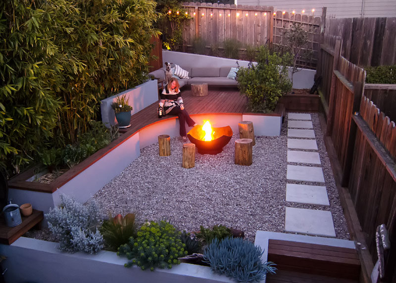 This modern landscaped backyard has a raised outdoor lounge deck, a wood burning firepit, succulents, bamboo and a vegetable garden.