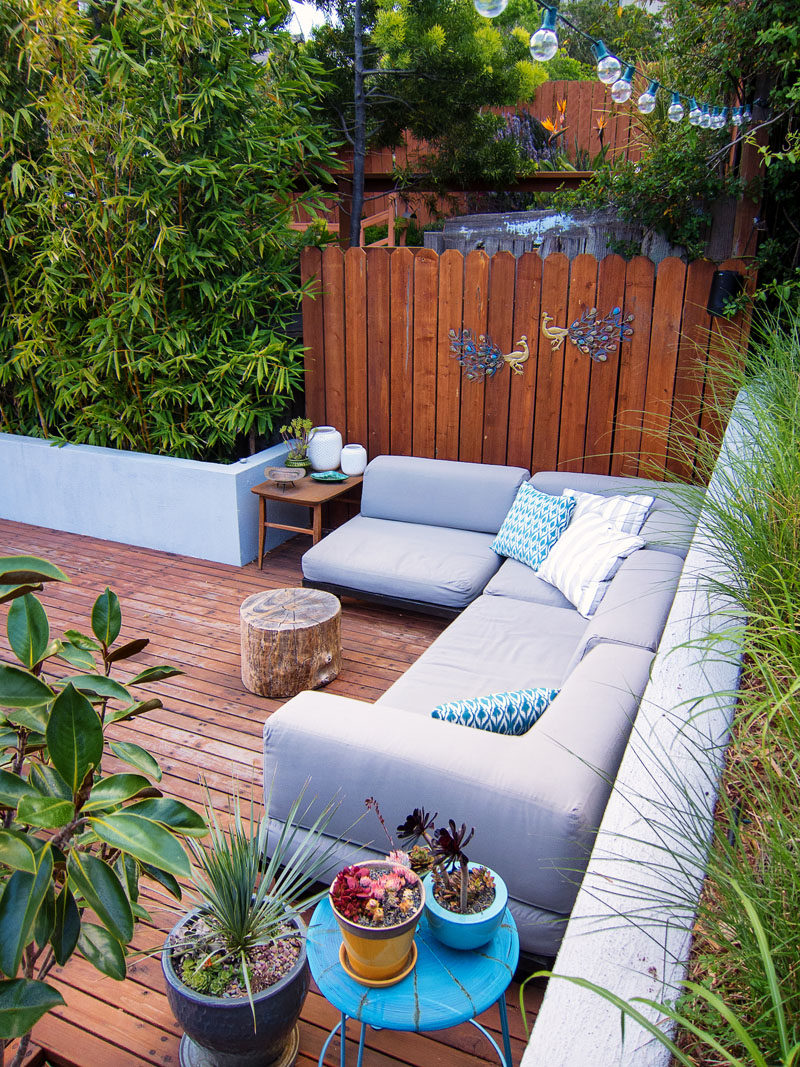 This modern landscaped backyard has a raised outdoor lounge deck, a wood burning firepit, succulents, bamboo and a vegetable garden.