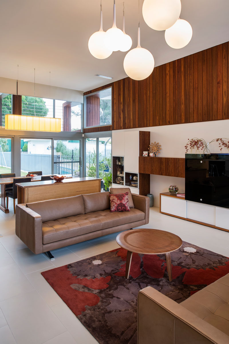 Behind this modern formal living room is the dining room, that's separated by a sideboard. The dining room sits next to large windows and a sliding door that leads out to the backyard.