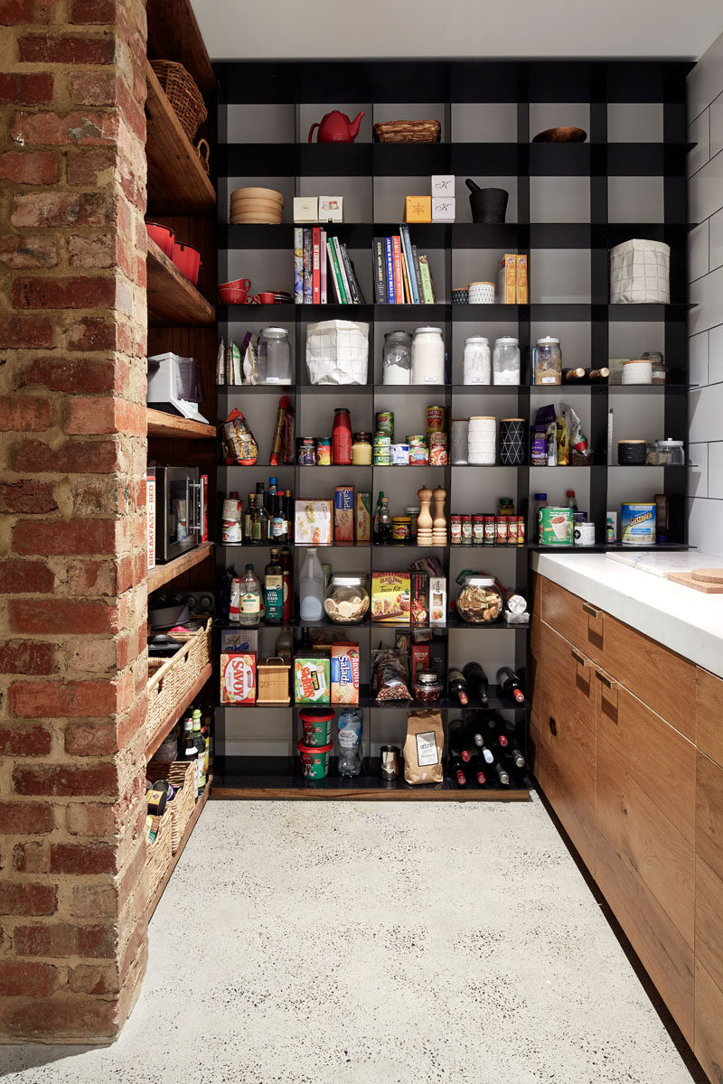 This modern pantry has open black steel shelving as well as recycled wood shelving. Polished concrete floors are used throughout the main floor of the home.