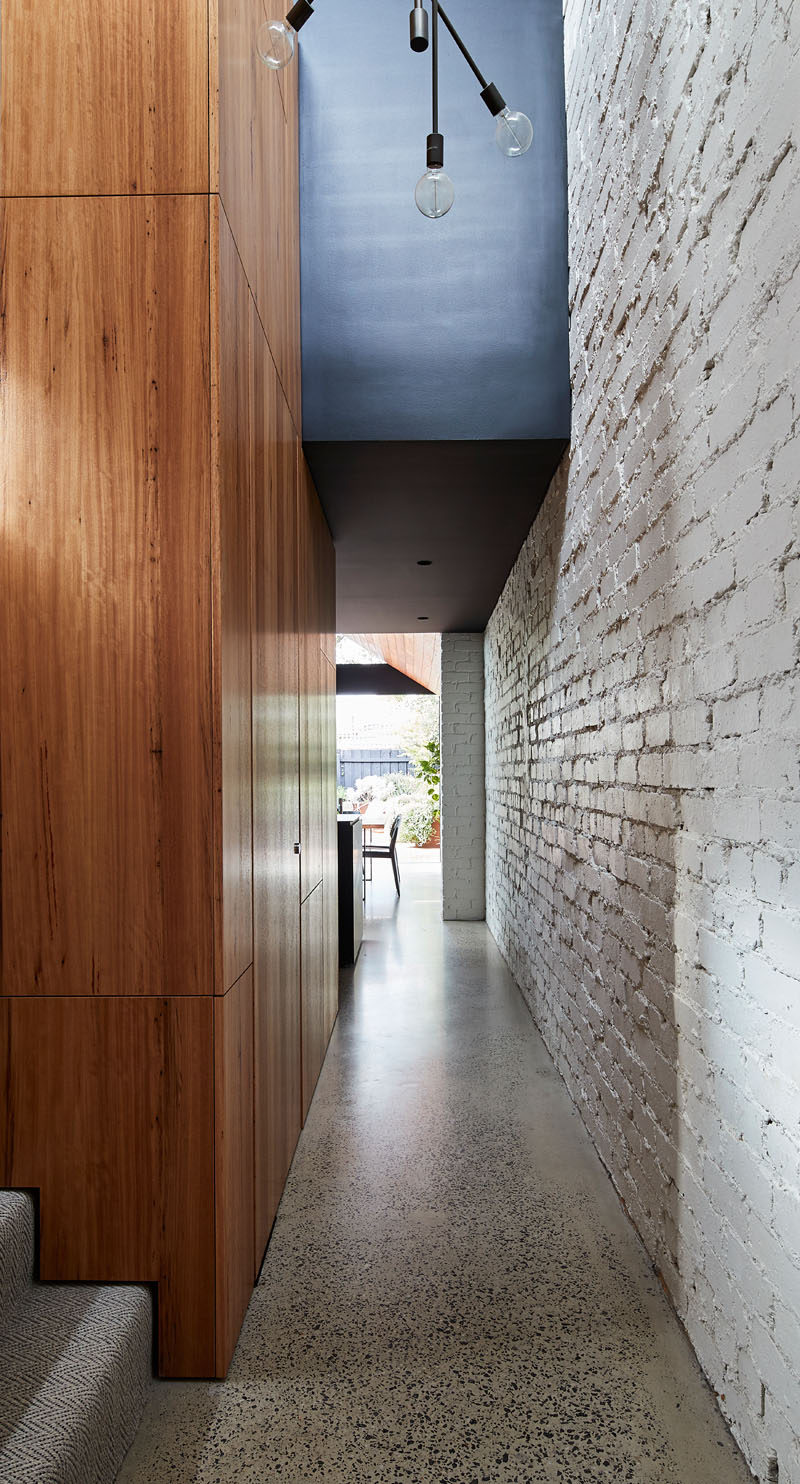 White painted brick and wood line this hallway in a renovated house.