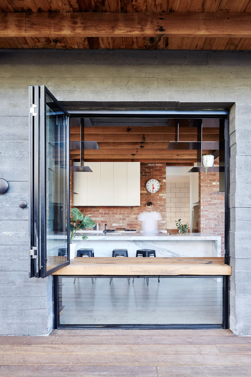 Exposed concrete surrounds a window with a wood ledge and when the window is open, it can be used as a counter or desk.