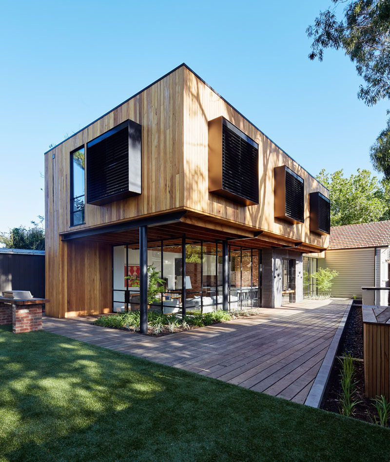 At the rear of this modern house extension, there's an outdoor space for indoor/outdoor living. Black framed windows provide a glimpse of the interior, while a swimming pool provides a place to cool off.