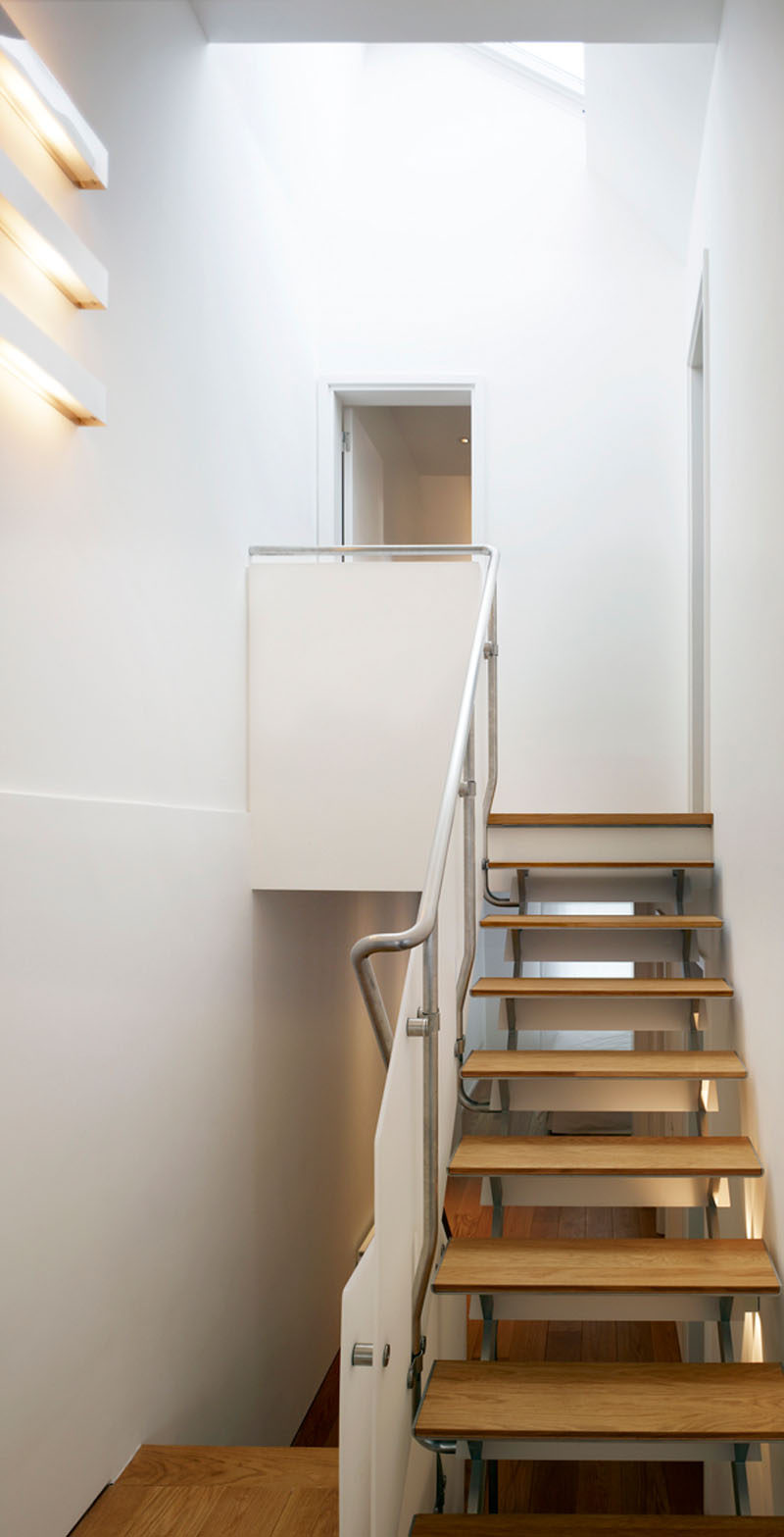 The stairs that connect the various floors of this renovated house have been named the Tin Tab Staircase, as the treads have been made into the slimmest treads possible to maximize transparency. From the top, the oak treads add warmth to the space, while from below, engineered blue stainless steel adds a cool touch. Simple bead-blasted handrails with a matte finish add to the contemporary design.