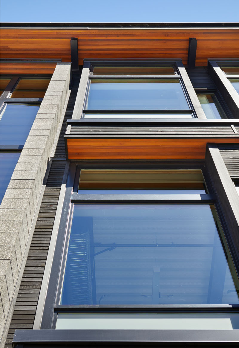 On the first and third floor of this live-work building, large glass panels project forward, while on the second floor, the glass panels are recessed. Custom-milled Western Red Cedar with a blackened stain have been used for the spandrel panels.