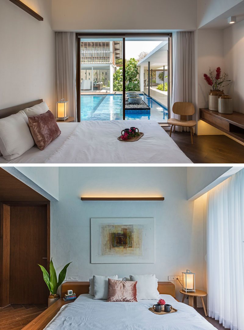 In this poolside modern bedroom, a simple wood light fixture adorns the wall, while a sliding glass door allows natural light and the breeze to enter the room.