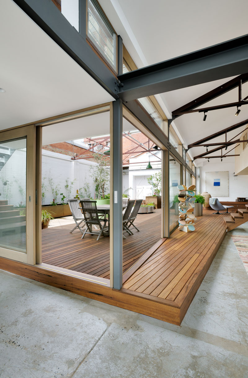 In this modern converted warehouse, a new raised wood deck connects the living areas of the home with the courtyard. Sliding glass doors and windows allow the sunlight to filter through to the interior.