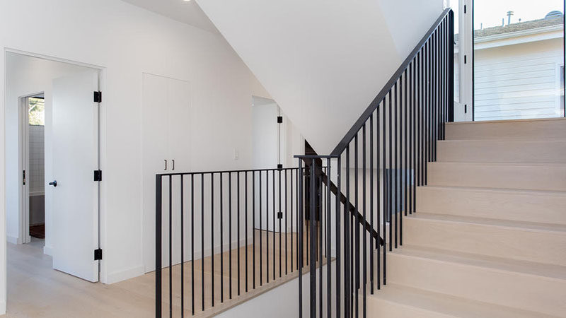 The stairs that connect the various levels of this modern house feature the same wide oak on the treads as the flooring, and black handrails tie in with the black door hardware.