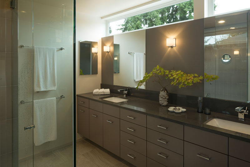 In this contemporary master bathroom, a large vanity with dual sinks runs the length of the room and a glass shower surround keeps the room feeling bright and airy.