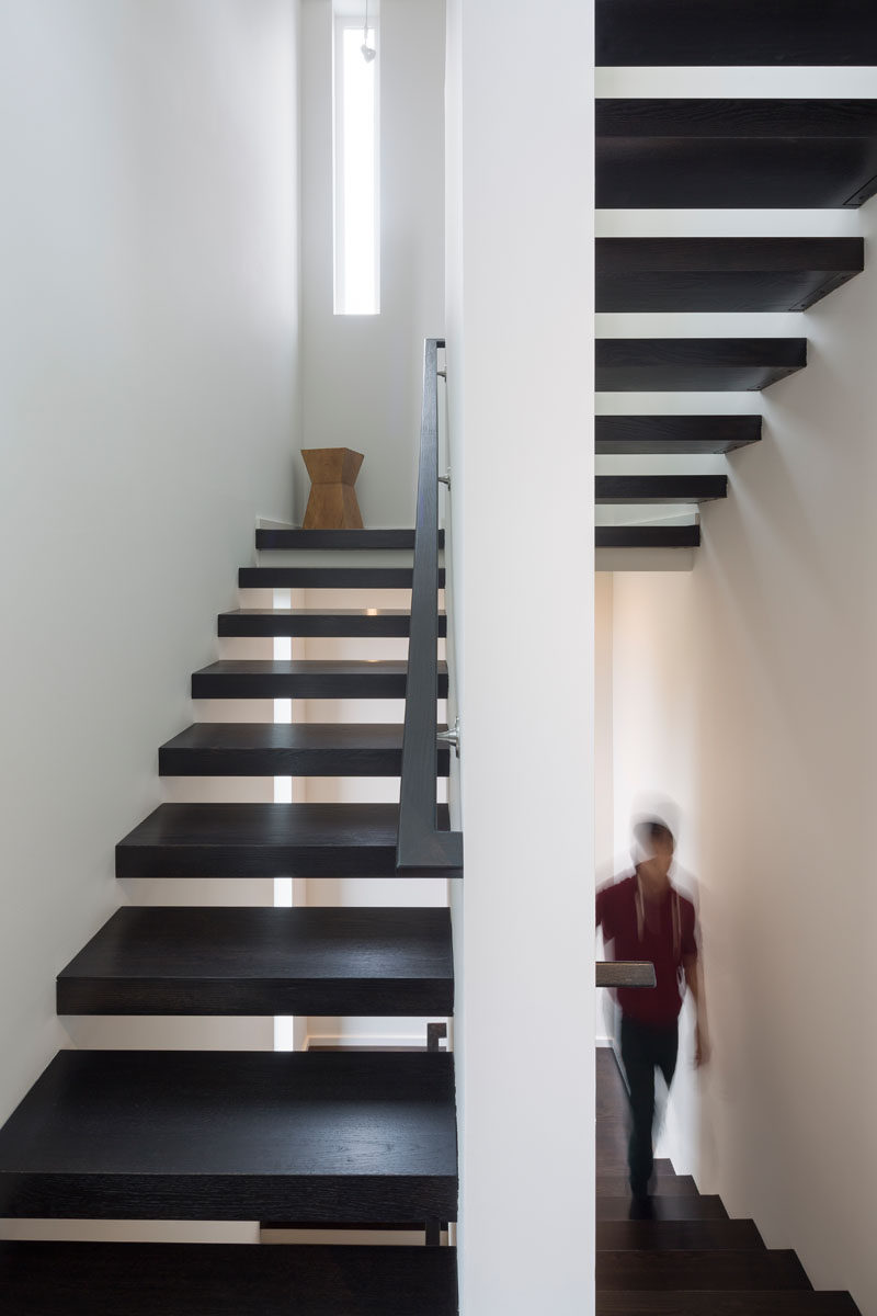 This set of modern stairs lead up to the sleeping areas of this house. Dark wood treads are a strong contrast to the white walls.