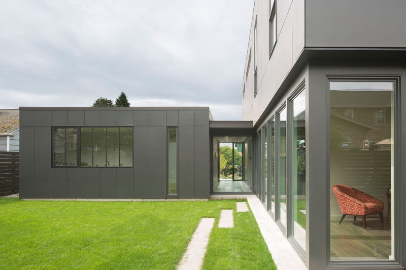 Sliding doors in the kitchen of this modern house open up to the grassy backyard. The backyard has a view of the laundry behind the garage and also a small media room, that's located next to the kitchen.