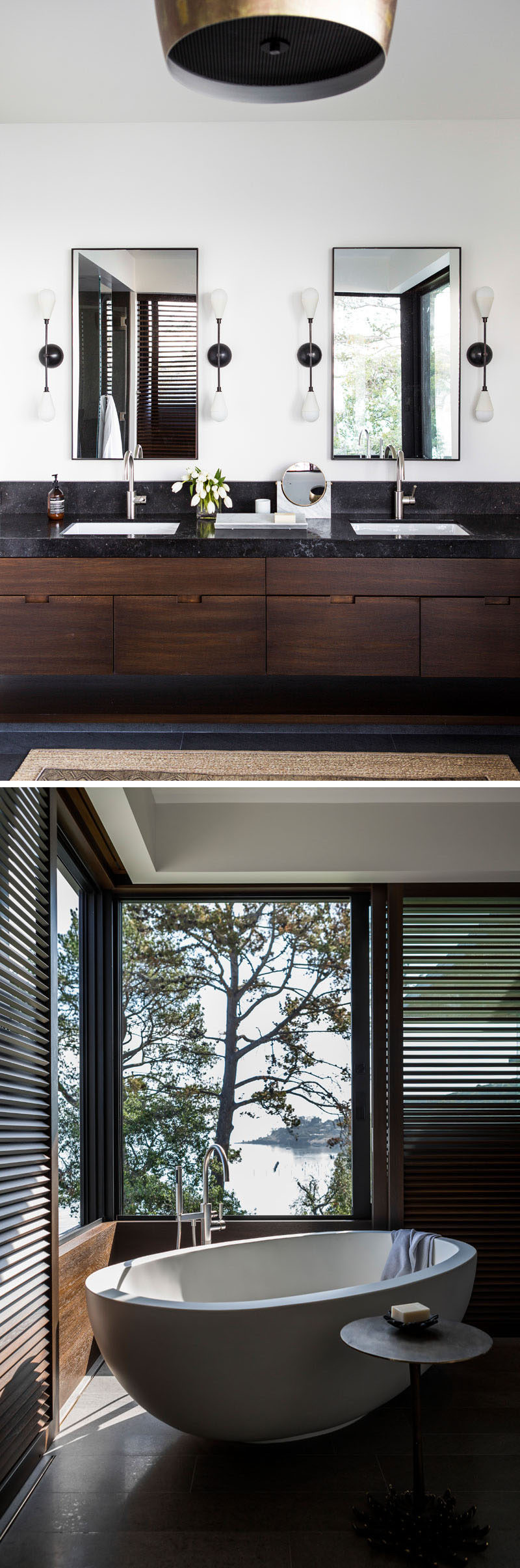 In this modern bathroom, two black-framed rectangular mirrors hang above a dual sink vanity, while sliding wood shutters can cover the windows for privacy when needed. #BathroomDesign #ModernBathroom #DarkWoodVanity #BlackCountertop