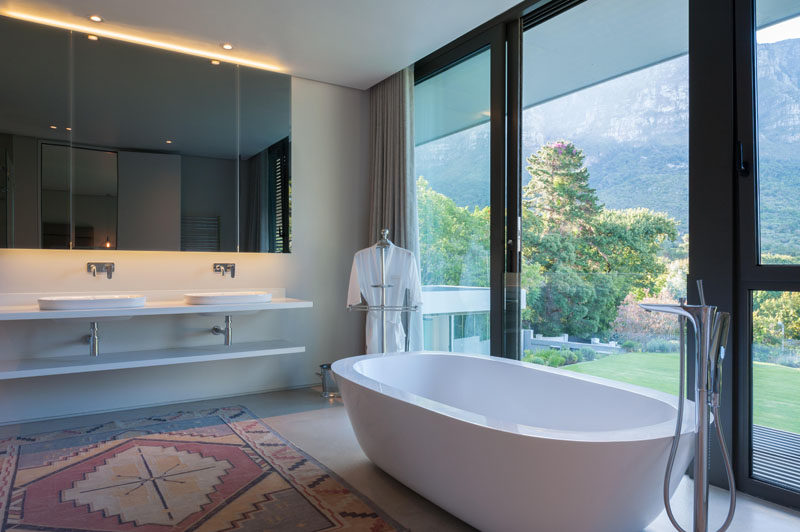 In the bathroom, a mirror with hidden lighting creates a calming atmosphere and the freestanding bathtub sits in front of the floor-to-ceiling windows to take advantage of the view.