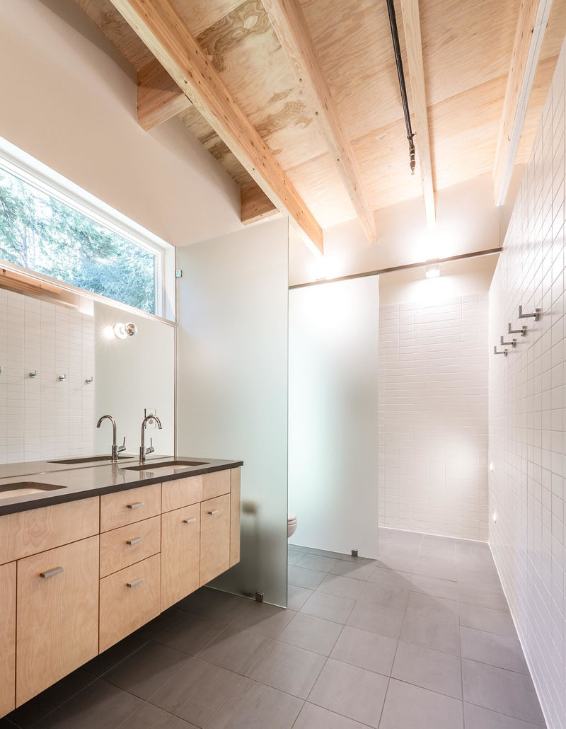 In this simple and modern bathroom, frosted glass partitions have been used to separate the toilet and the shower from the rest of the space.