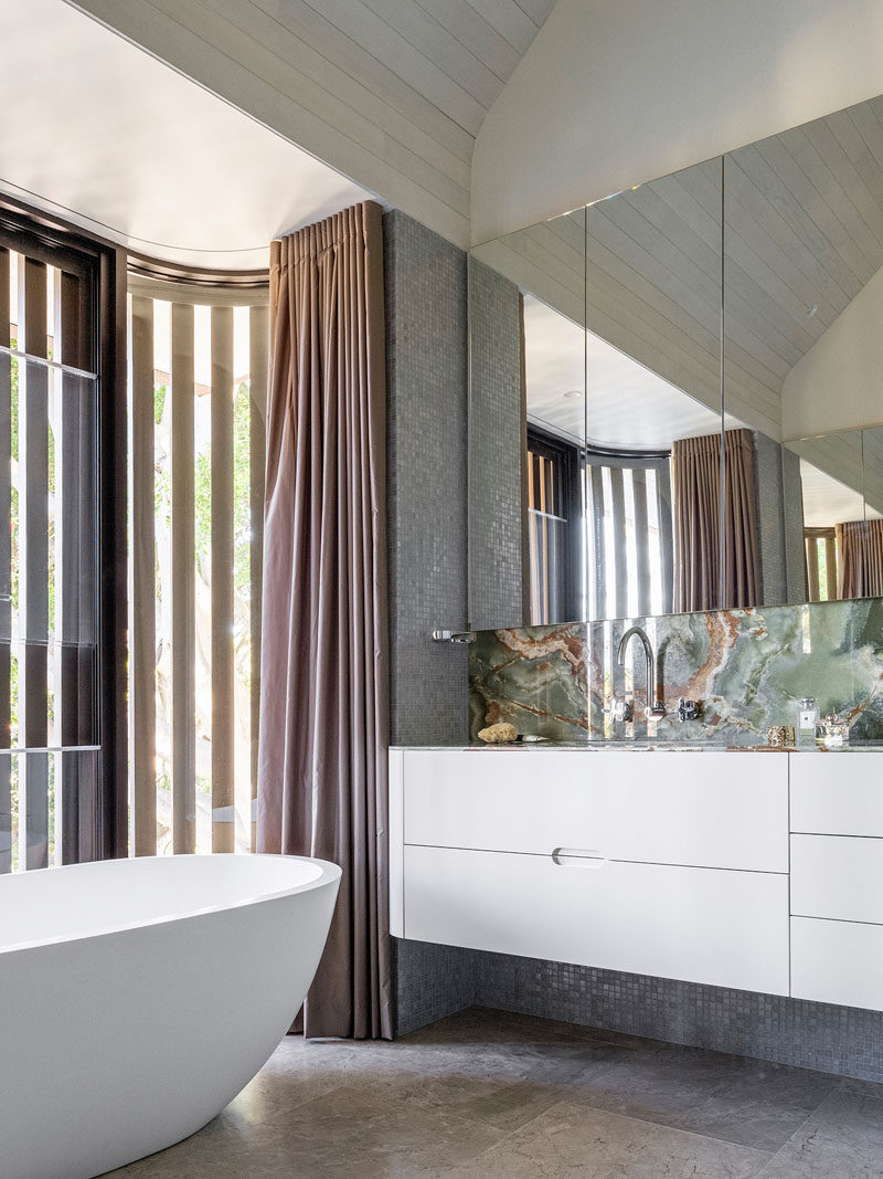 In this bathroom, green onyx has been used for a backsplash, while a white vanity and oval bathtub add a simple contemporary touch.