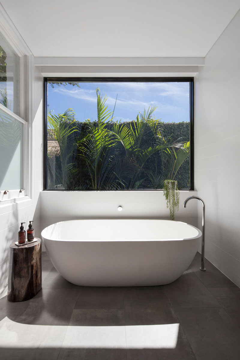 This modern bathroom extension has a large window that sits above a freestanding bathtub.