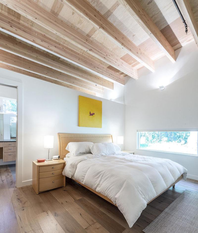 In this modern bedroom, high ceiling create a sense of openness, while the white walls are broken up with a bright yellow piece of artwork.