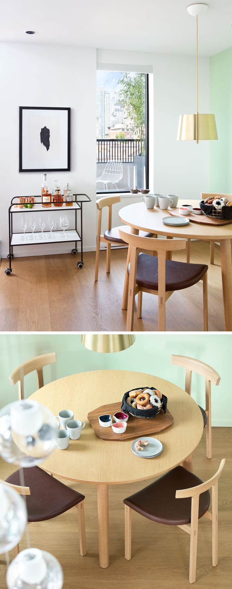 In this contemporary dining area, a light green wall becomes the backdrop for the wood dining table and chairs, and a simple black framed bar cart ties in with the black window frame and artwork hanging above it.