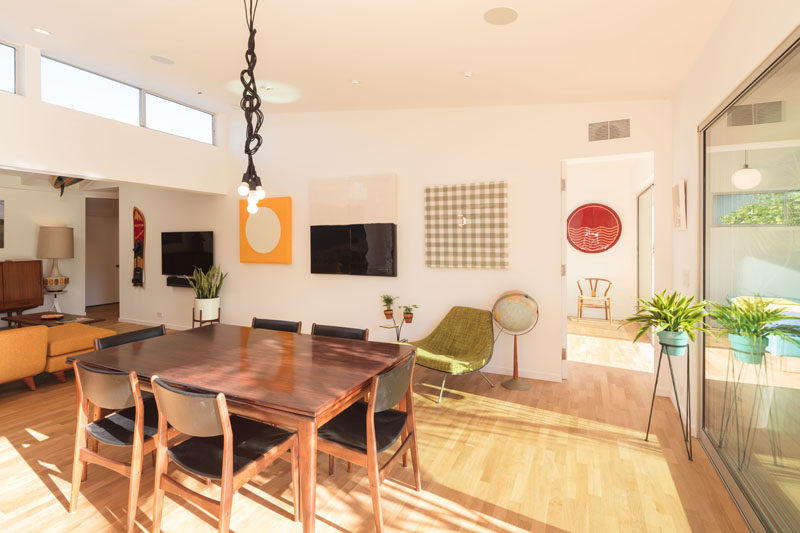 In this modern dining room, clerestory windows add additional light, while a dark wood dining table matches some of the dark wood furniture in the living room.