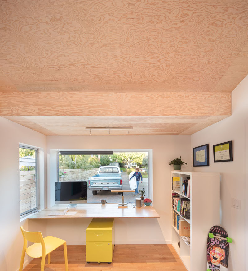 This home office that has a large window with a desk beneath it that looks out onto the driveway and street. 