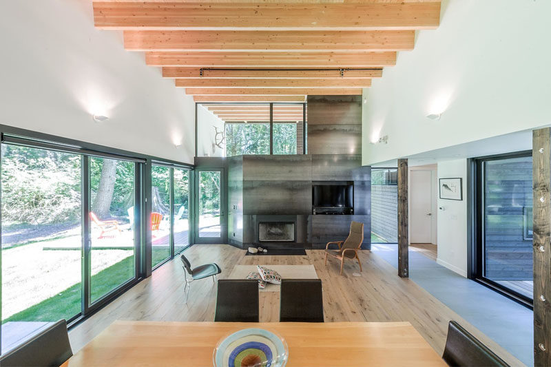 Design as a zen-like retreat from the city, the interior of this modern house features high ceilings that make the interior feel large and open. Exposed wood beams and a steel clad fireplace add warmth to the space, while windows let in plenty of natural light.