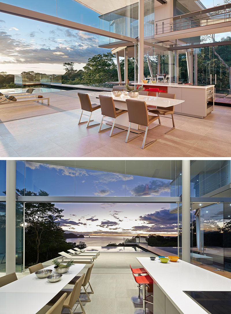 Separating the living room from the kitchen in this modern house, is the dining area. A simple white dining table is surrounded by tan dining chairs, and the dining area opens up to the deck and pool.